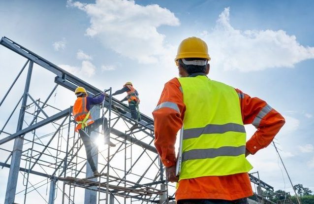 Engineer technician watching team of workers on high steel platform.